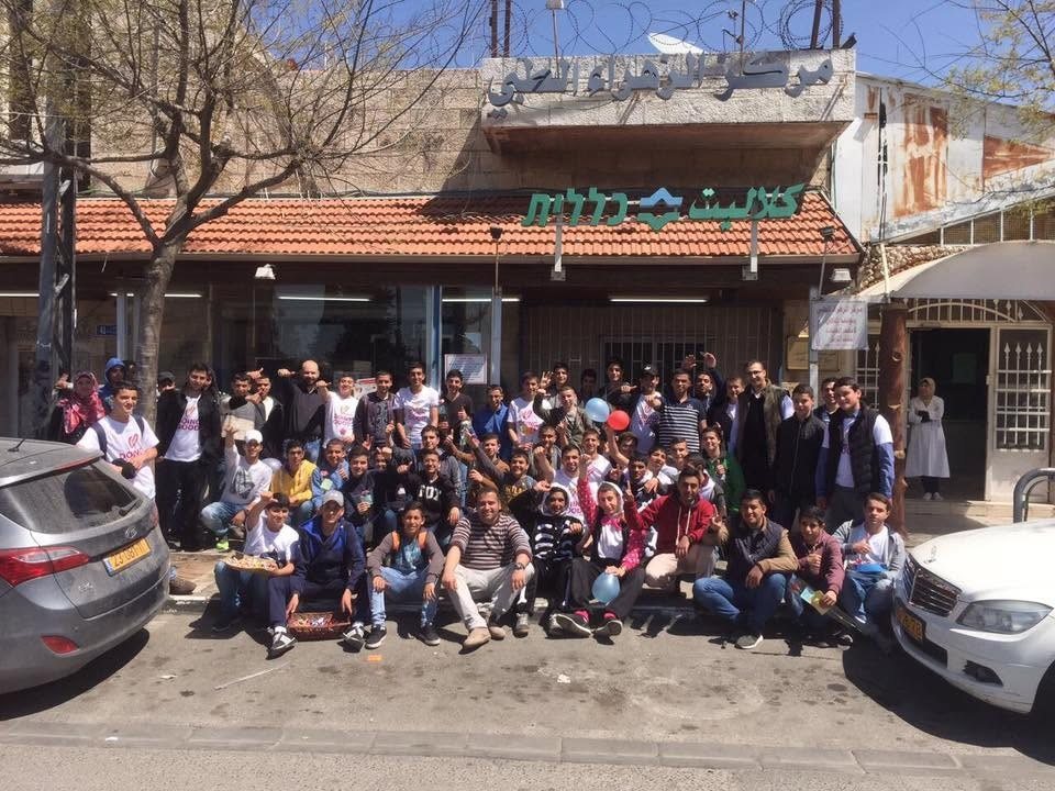 طلاب ومتطوعون أمام مبنى مركز الزهراء الطبي في شعفاط